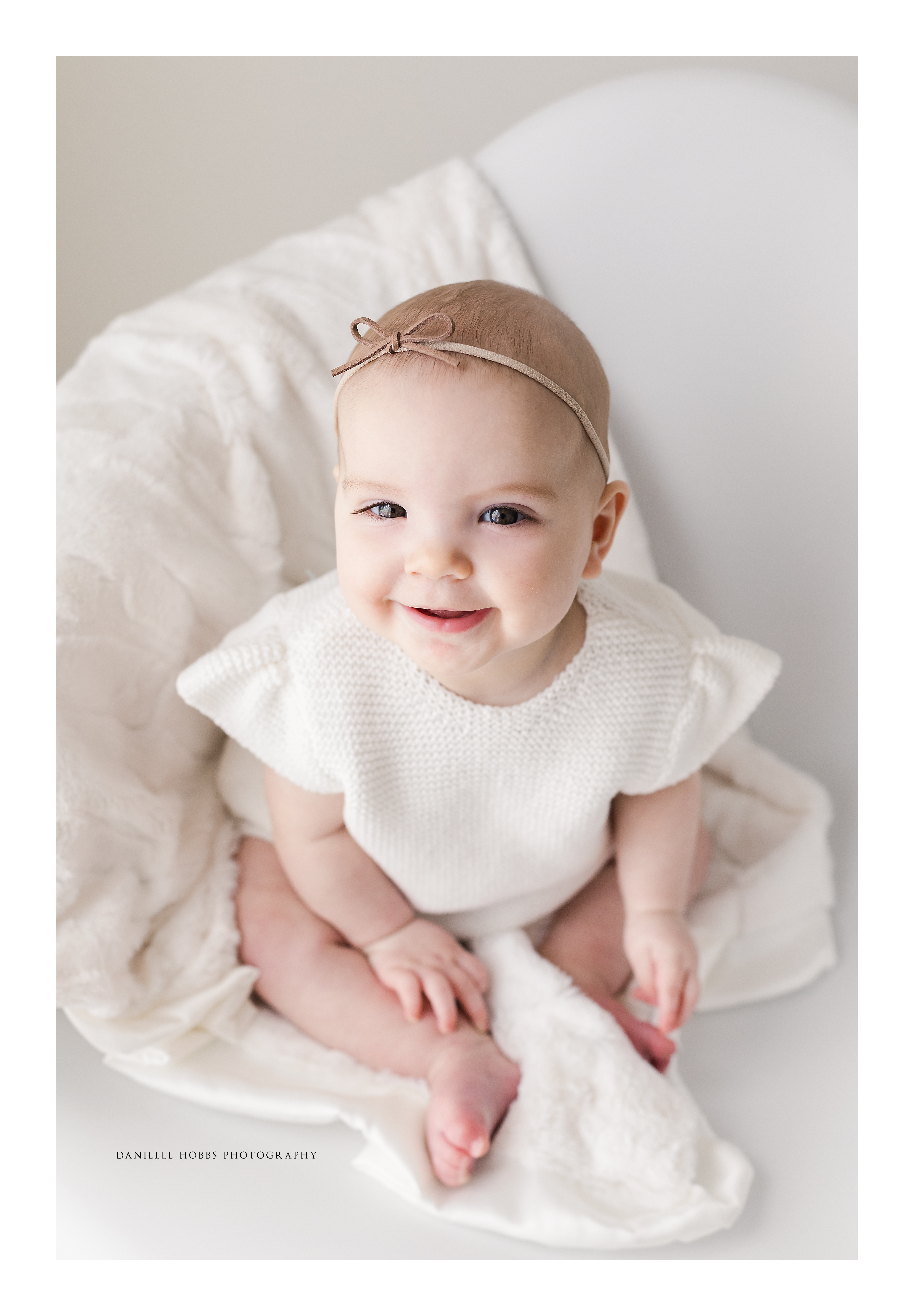 Baby girl smiling in white chair on minky blanket from Minky Couture
